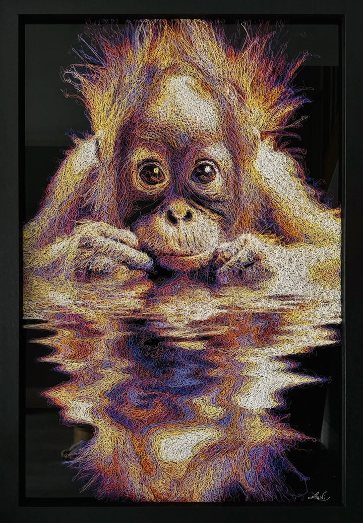 A vibrant textured artwork of a baby orangutan leaning over shimmering water, created with Zalini’s intricate injected-scribble technique, featuring flowing multicoloured lines, bright orange fur, vivid purples and blues, and a mirrored reflection across a glossy black surface.