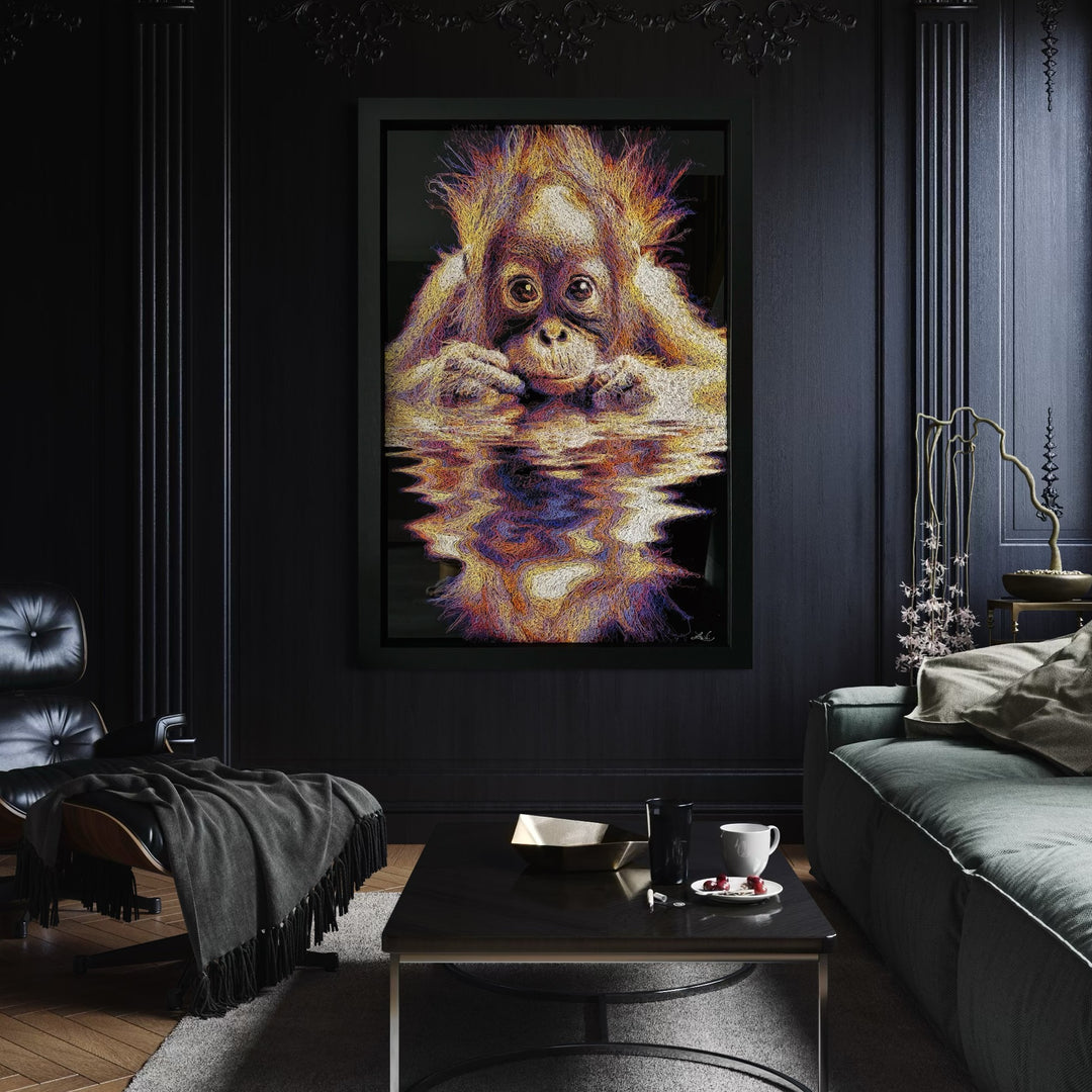 A vibrant textured artwork of a baby orangutan leaning over shimmering water, created with Zalini’s intricate injected-scribble technique, featuring flowing multicoloured lines, bright orange fur, vivid purples and blues, and a mirrored reflection across a glossy black surface.