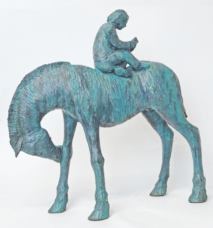 Lost in the Calmness of Reading by Ian Marlow - a limited edition bronze sculpture depicting a young figure seated atop a grazing horse, absorbed in a book, with a textured surface and serene presence.