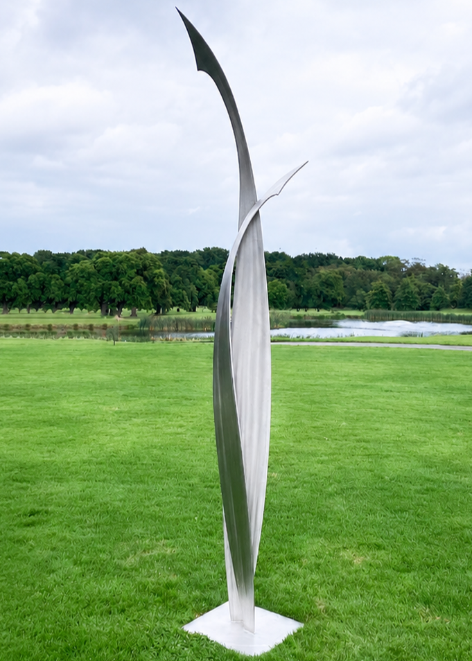 Ian Marlow MRSS stainless steel sculpture Rising Together, featuring two tall, sweeping abstract forms that curve upwards and meet within an elegant contemporary composition, displayed outdoors within a landscaped garden setting.