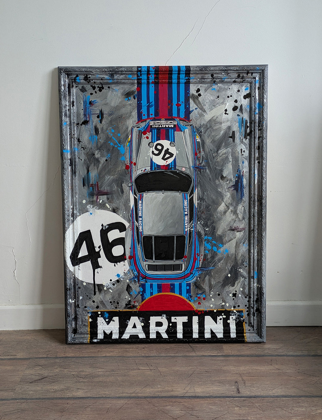 Original painting of a 1973 Porsche 911 Carrera 3.0 RSR in Martini Racing livery, shown from a top-down view with bold racing stripes and number 46, set against a textured abstract grey background and framed in a custom-painted frame.