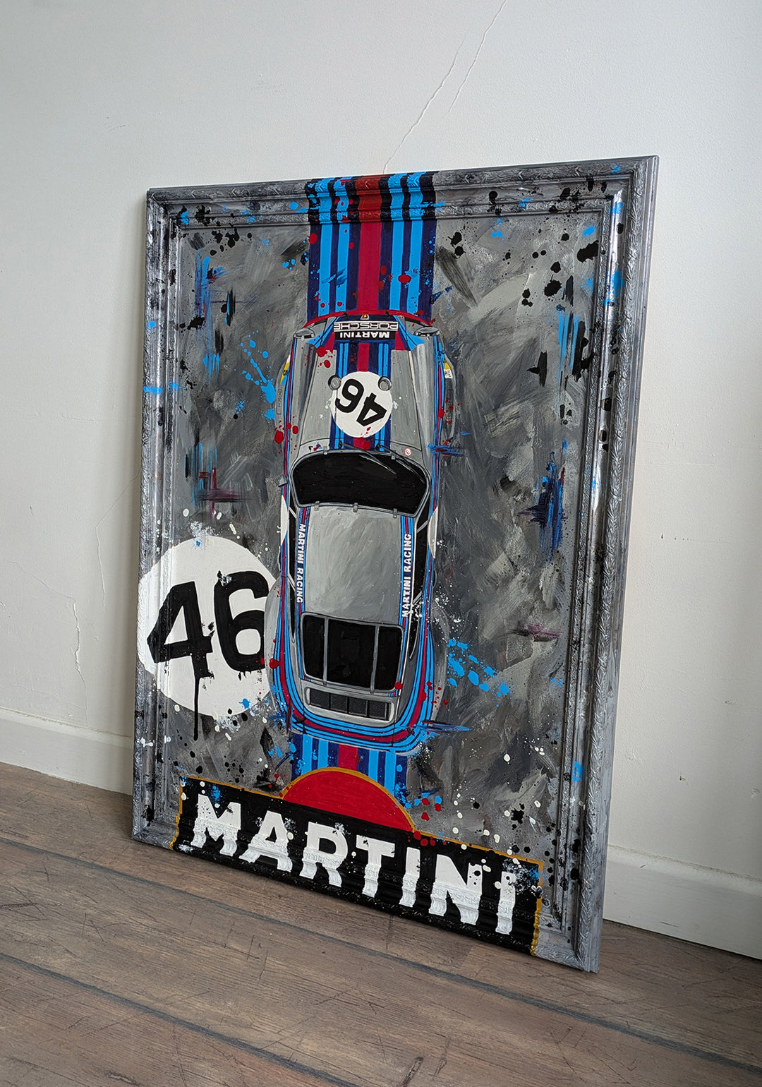 Original painting of a 1973 Porsche 911 Carrera 3.0 RSR in Martini Racing livery, shown from a top-down view with bold racing stripes and number 46, set against a textured abstract grey background and framed in a custom-painted frame.