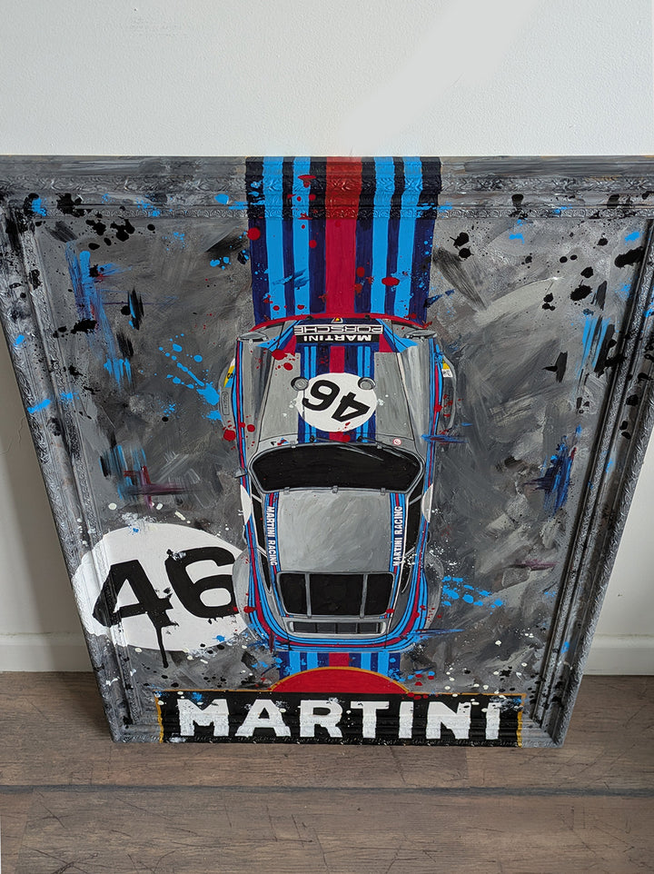 Original painting of a 1973 Porsche 911 Carrera 3.0 RSR in Martini Racing livery, shown from a top-down view with bold racing stripes and number 46, set against a textured abstract grey background and framed in a custom-painted frame.