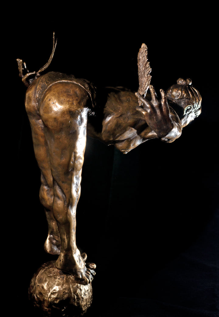 Ingenuity: Often thwarted by the shortsighted by Teresa Wells – a limited-edition bronze and steel sculpture depicting a poised, athletic female figure balanced on tiptoe atop a textured bronze sphere. The figure leans dramatically forward from the hips, arms extended behind and slightly upward, each hand delicately holding a detailed bronze feather. Muscular contours and tendons are rendered with lifelike precision, from the arched spine to the curled toes gripping the sphere. 