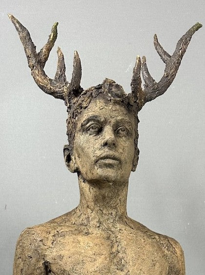 Contemporary ceramic full-figure sculpture by Eve Shepherd depicting a standing male figure with antlers, merging human and animal forms, featuring raw hand-built clay textures, bare torso, distressed blue trousers and an earth-toned base, exploring instinct, identity and the tension between civilisation and primal nature