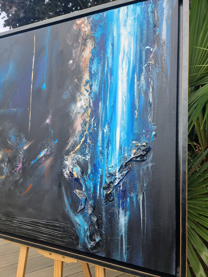 Abstract mixed-media painting in deep blues and blacks with cascading vertical textures, bright aqua highlights and metallic gold accents, featuring layered fabric elements that create a sense of movement and depth against a dark atmospheric background.