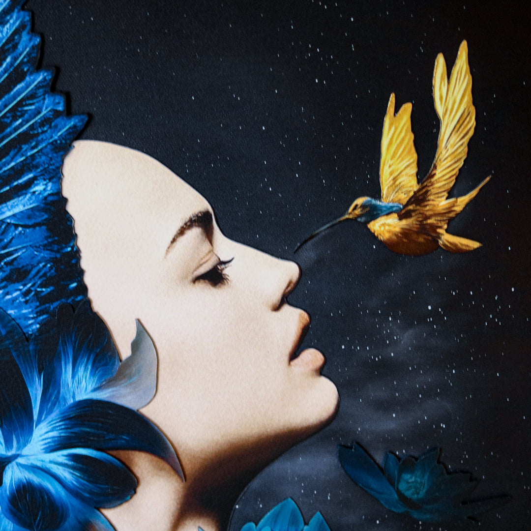 Catarina Diaz’s I See, an analogue collage on Somerset Enhanced Velvet with oil on canvas board. A serene female profile adorned with vivid blue feathers and lotus blooms faces a golden-yellow hummingbird, all set against a starry black backdrop in an antique gallery frame.