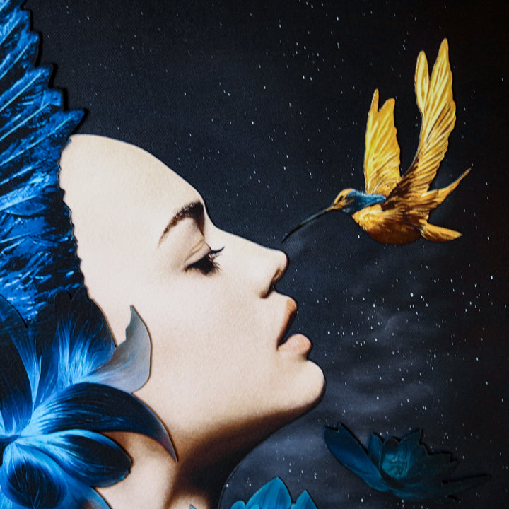Catarina Diaz’s I See, an analogue collage on Somerset Enhanced Velvet with oil on canvas board. A serene female profile adorned with vivid blue feathers and lotus blooms faces a golden-yellow hummingbird, all set against a starry black backdrop in an antique gallery frame.