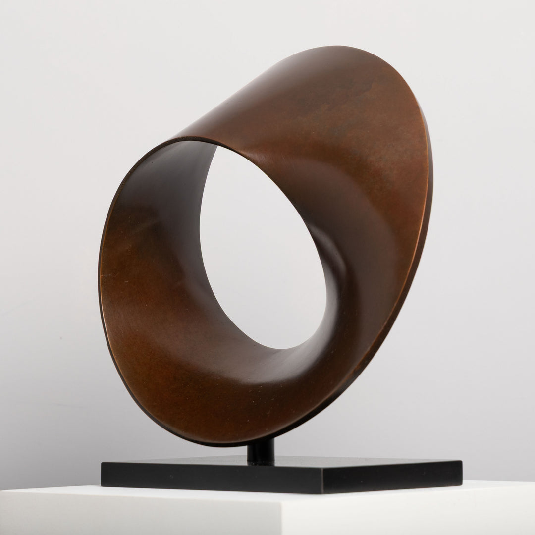 Patinated bronze Continuum sculpture by James Parker, formed as a flowing Möbius loop with a continuous twisting surface and crescent-like profile.