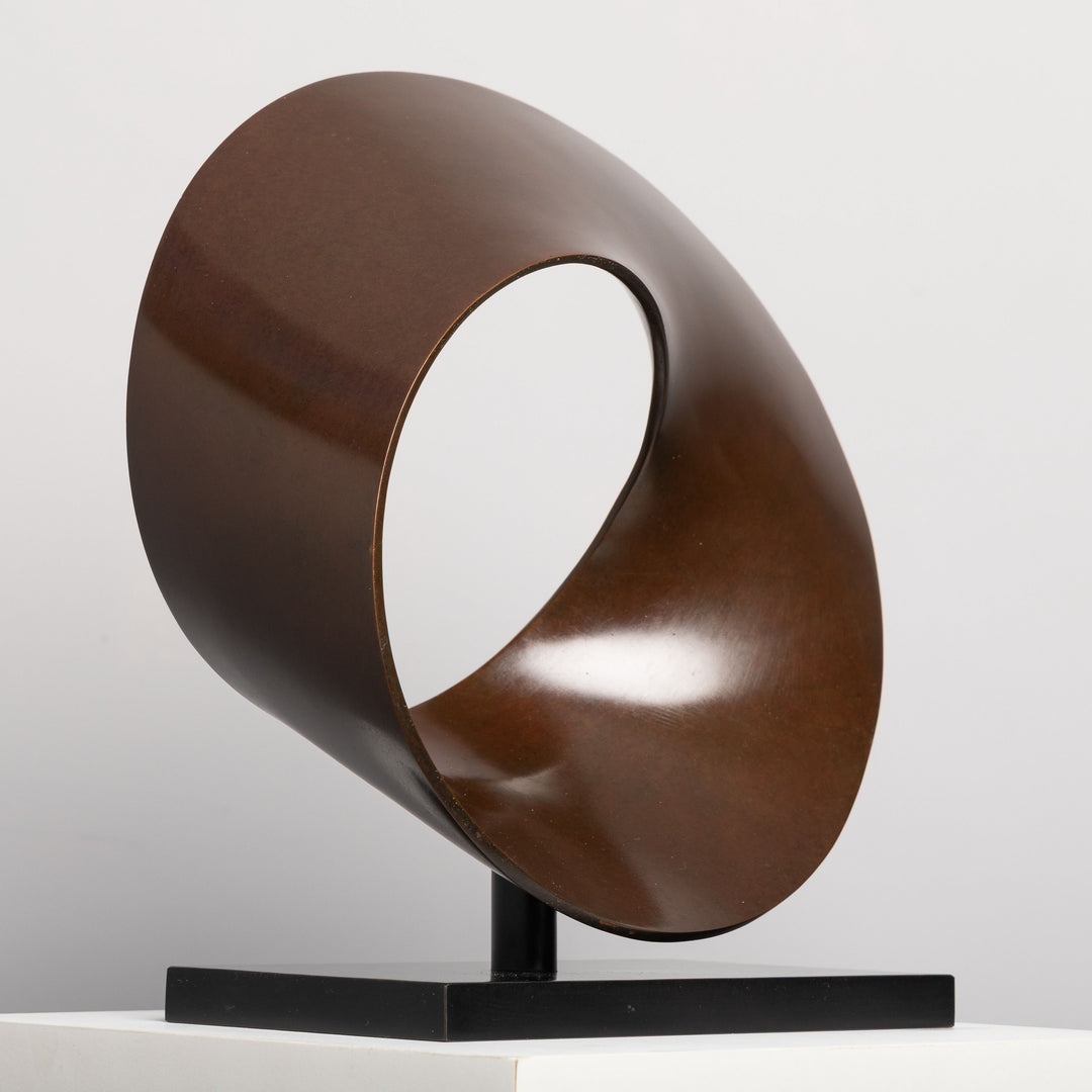Patinated bronze Continuum sculpture by James Parker, formed as a flowing Möbius loop with a continuous twisting surface and crescent-like profile.