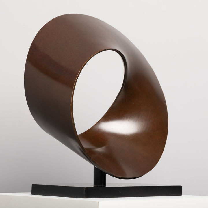 Patinated bronze Continuum sculpture by James Parker, formed as a flowing Möbius loop with a continuous twisting surface and crescent-like profile.