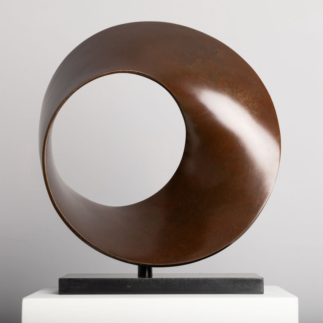 Patinated bronze Continuum sculpture by James Parker, formed as a flowing Möbius loop with a continuous twisting surface and crescent-like profile.