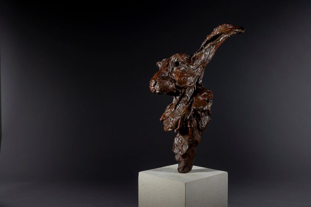 Expressive bronze sculpture of a hare’s head with exaggerated upright ears, mounted on a smooth Portland stone base.