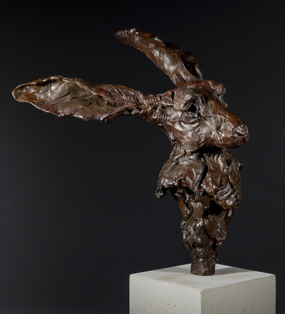 Expressive bronze sculpture of a hare’s head with exaggerated upright ears, mounted on a smooth Portland stone base.