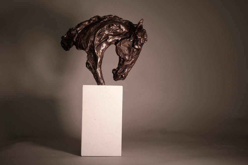 Bronze sculpture of an arched horse head with expressive detailing, mounted on a minimalist Portland stone base against a soft neutral backdrop.