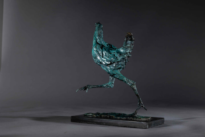 Bronze sculpture of a proud gaming cockerel mid-stride, with elongated legs and intricate feather textures, finished in a rich verdigris patina, mounted on a slate base.
