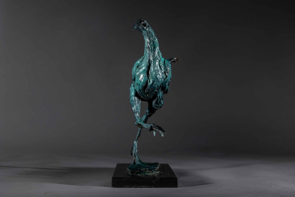 Bronze sculpture of a proud gaming cockerel mid-stride, with elongated legs and intricate feather textures, finished in a rich verdigris patina, mounted on a slate base.
