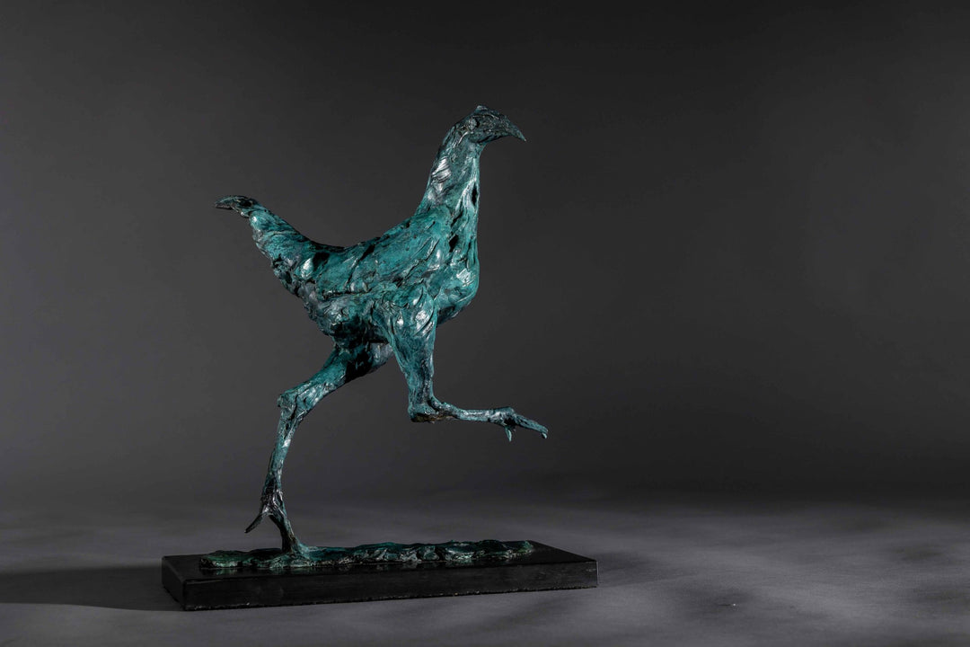 Bronze sculpture of a proud gaming cockerel mid-stride, with elongated legs and intricate feather textures, finished in a rich verdigris patina, mounted on a slate base.