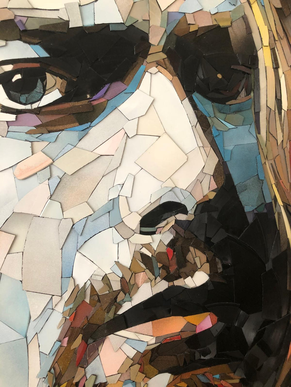 Ed Chapman mosaic portrait of Kurt Cobain crafted entirely from broken vinyl records, with layered shards forming a striking likeness of the Nirvana frontman against a soft pink background.