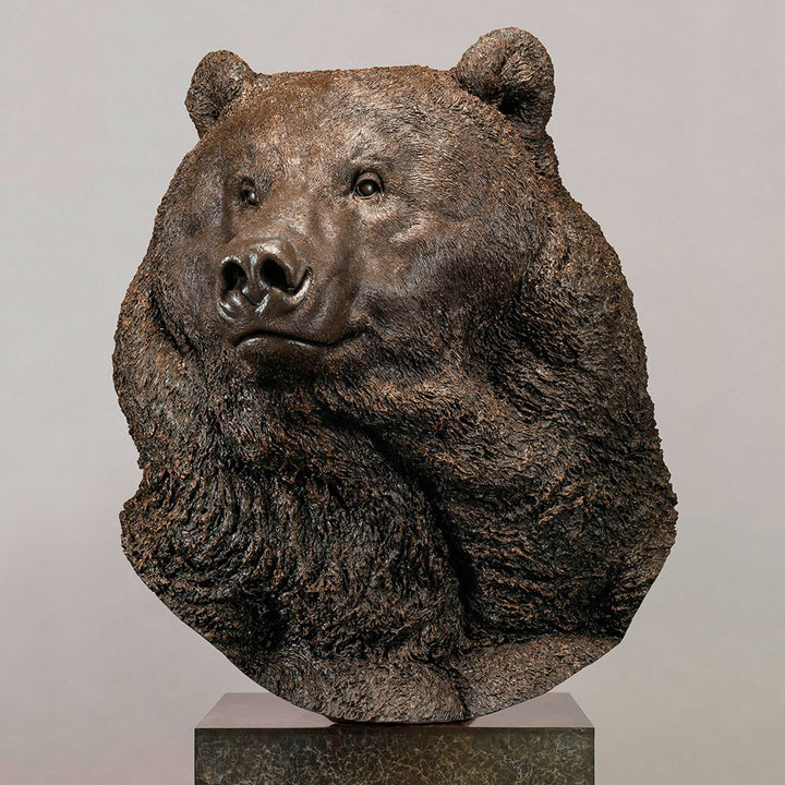 Large bronze head study of a Kodiak brown bear by Nick Bibby, showing powerful form, dense textured fur and rich brown patina, mounted on a tall bronze plinth with mottled green and earthy tones.