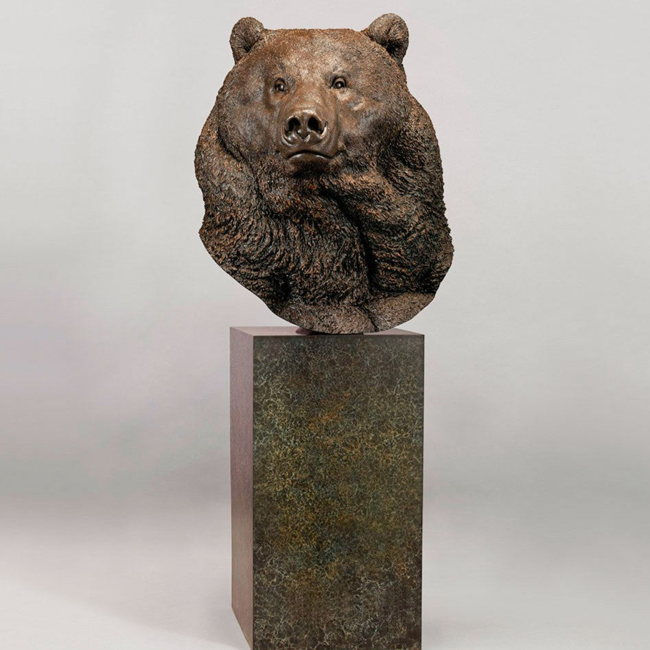 Large bronze head study of a Kodiak brown bear by Nick Bibby, showing powerful form, dense textured fur and rich brown patina, mounted on a tall bronze plinth with mottled green and earthy tones.