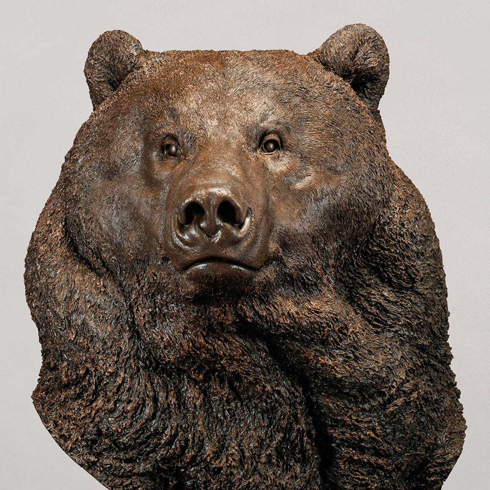Large bronze head study of a Kodiak brown bear by Nick Bibby, showing powerful form, dense textured fur and rich brown patina, mounted on a tall bronze plinth with mottled green and earthy tones.