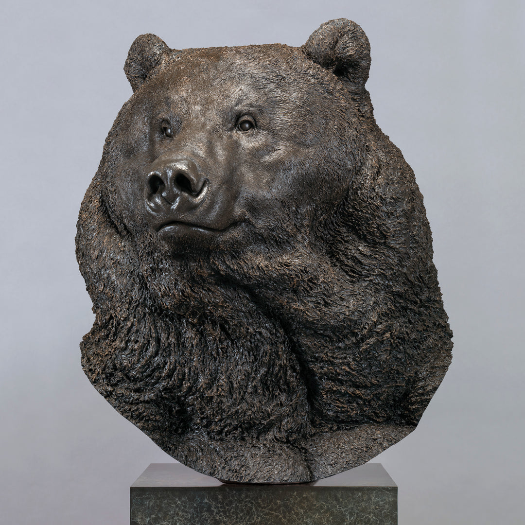 Large bronze head study of a Kodiak brown bear by Nick Bibby, showing powerful form, dense textured fur and rich brown patina, mounted on a tall bronze plinth with mottled green and earthy tones.