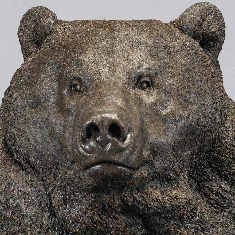 Large bronze head study of a Kodiak brown bear by Nick Bibby, showing powerful form, dense textured fur and rich brown patina, mounted on a tall bronze plinth with mottled green and earthy tones.