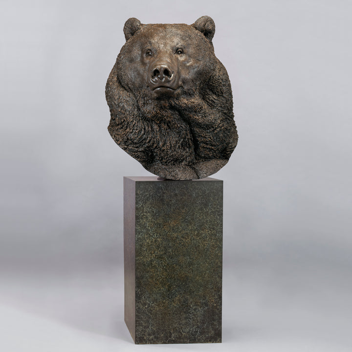 Large bronze head study of a Kodiak brown bear by Nick Bibby, showing powerful form, dense textured fur and rich brown patina, mounted on a tall bronze plinth with mottled green and earthy tones.
