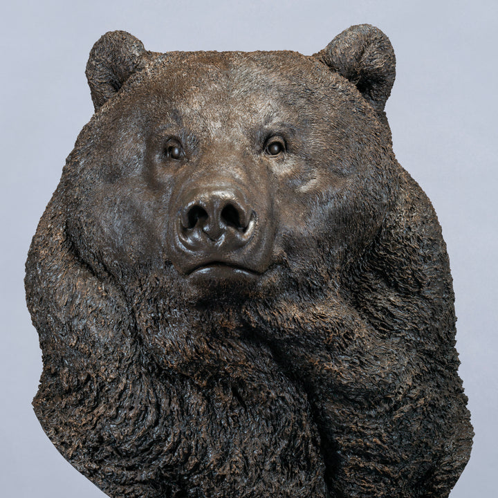 Large bronze head study of a Kodiak brown bear by Nick Bibby, showing powerful form, dense textured fur and rich brown patina, mounted on a tall bronze plinth with mottled green and earthy tones.