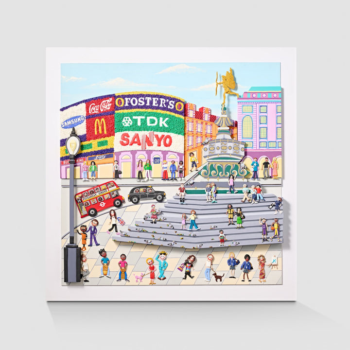 A vibrant, three-dimensional polymer clay artwork of Piccadilly Circus, featuring the iconic curved billboard with brands like Coca-Cola, McDonald’s, and TDK rendered in colourful textured beads. The street scene below includes a classic red double-decker bus marked “38 Piccadilly Circus,” a London black cab, and crowds of joyful figures in bright handmade outfits. Sculpted pigeons dot the grey stone steps beneath the Shaftesbury Memorial Fountain with a golden winged Eros above. 