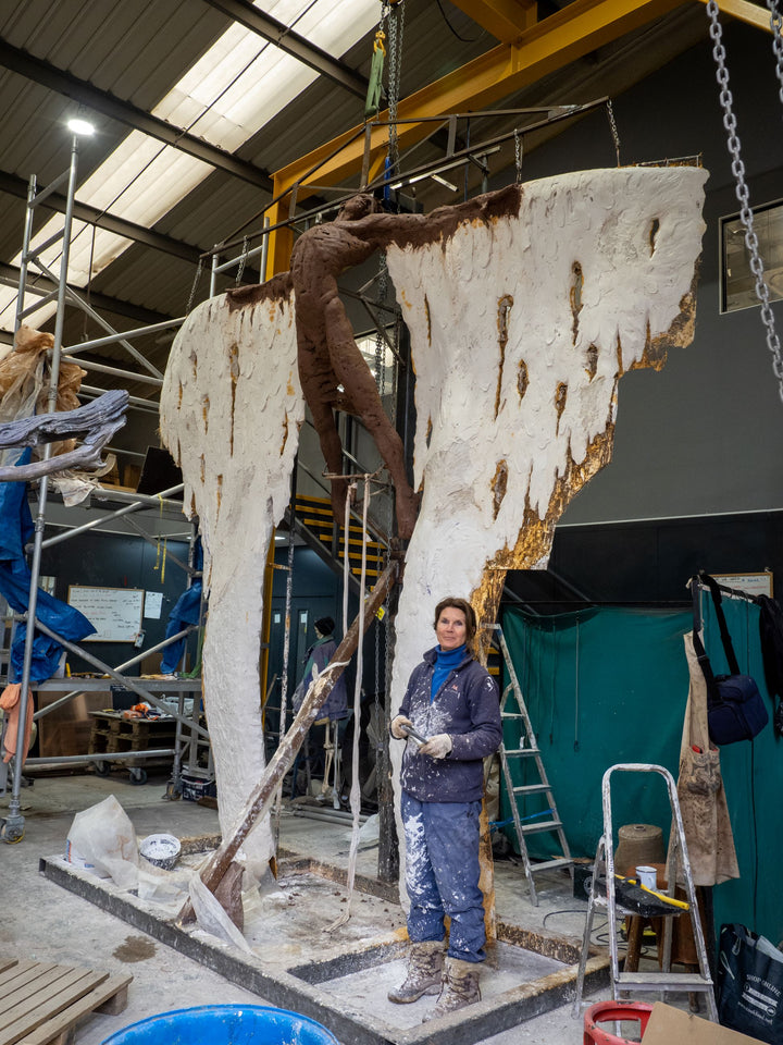 Costruction phases during creation. Monumental bronze sculpture of Icarus mid-flight with expansive feathered wings, captured in an expressive upward pose against a bright sky and lush garden backdrop.