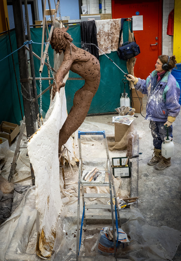 Costruction phases during creation. Monumental bronze sculpture of Icarus mid-flight with expansive feathered wings, captured in an expressive upward pose against a bright sky and lush garden backdrop.