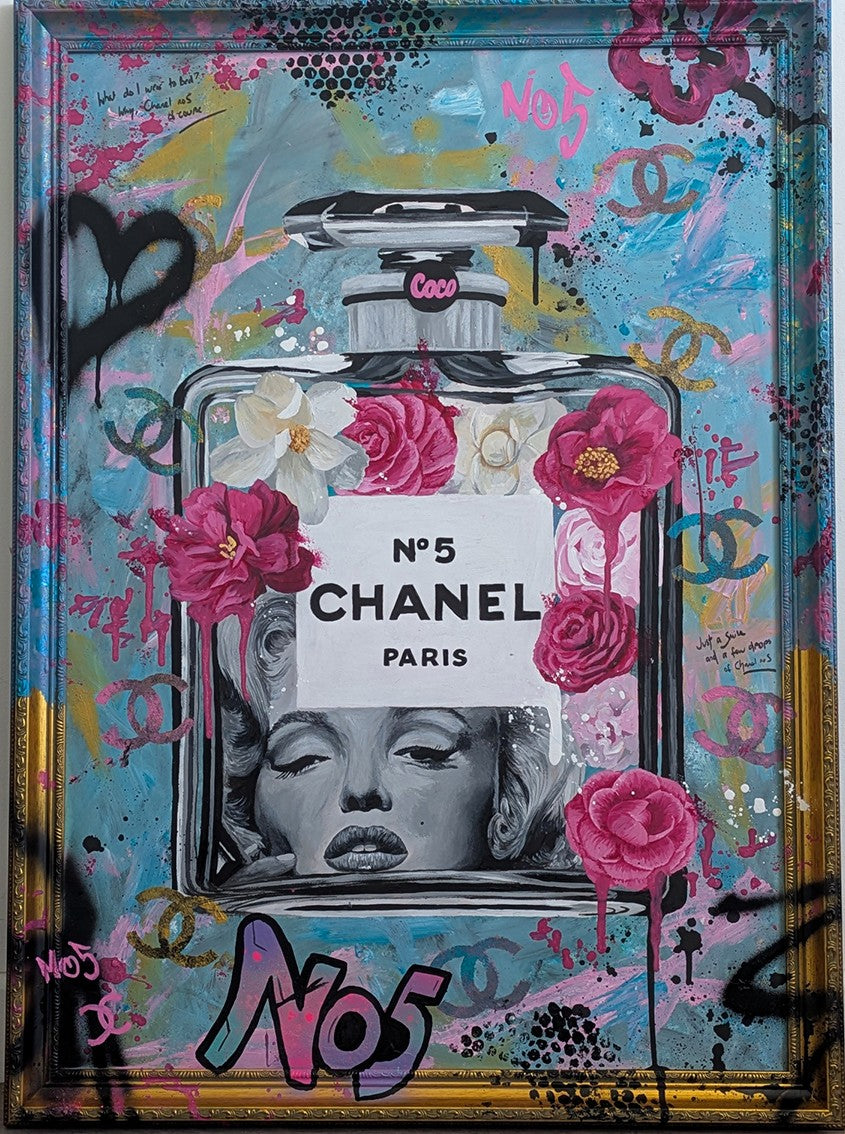 "Marilyn Monroe X Chanel No.5" – a bold embellished art print by Ian Salmon, featuring a black-and-white portrait of Marilyn Monroe embedded in a painted Chanel No.5 bottle, surrounded by vivid pink and red Camellia flowers, graffiti-style branding, and set against a turquoise, pastel blue, and gold accented background with a hand-painted custom frame.