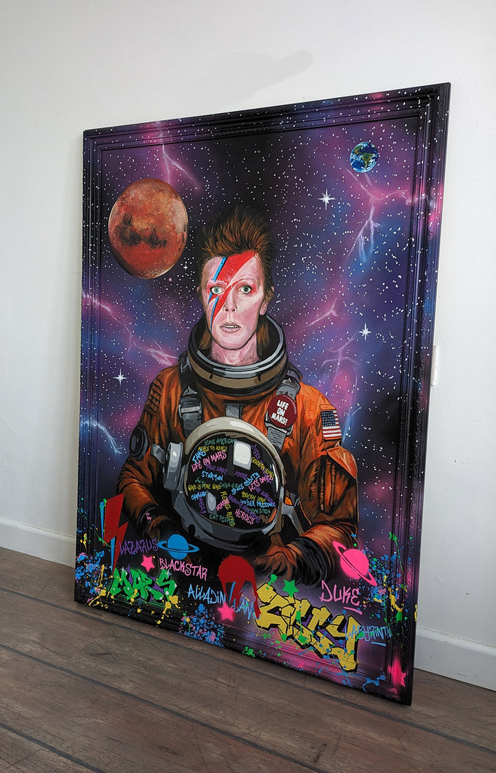 Limited edition embellished art print of David Bowie in a retro orange NASA-style spacesuit set against a vivid cosmic backdrop, featuring Mars and Earth, graffiti elements, and Bowie’s iconic lightning bolt makeup, created by KiPS.art and printed on 3mm Foamex.