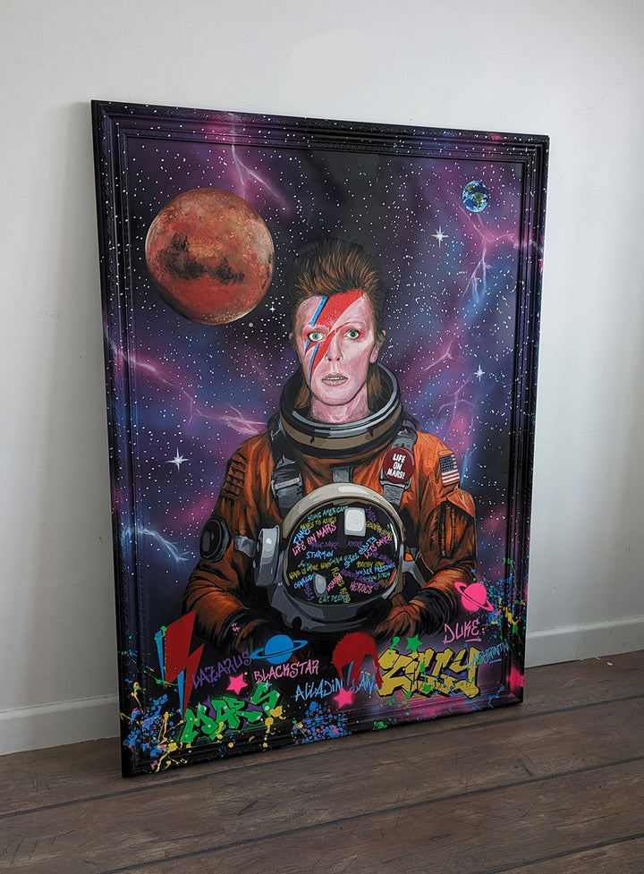 Limited edition embellished art print of David Bowie in a retro orange NASA-style spacesuit set against a vivid cosmic backdrop, featuring Mars and Earth, graffiti elements, and Bowie’s iconic lightning bolt makeup, created by KiPS.art and printed on 3mm Foamex.