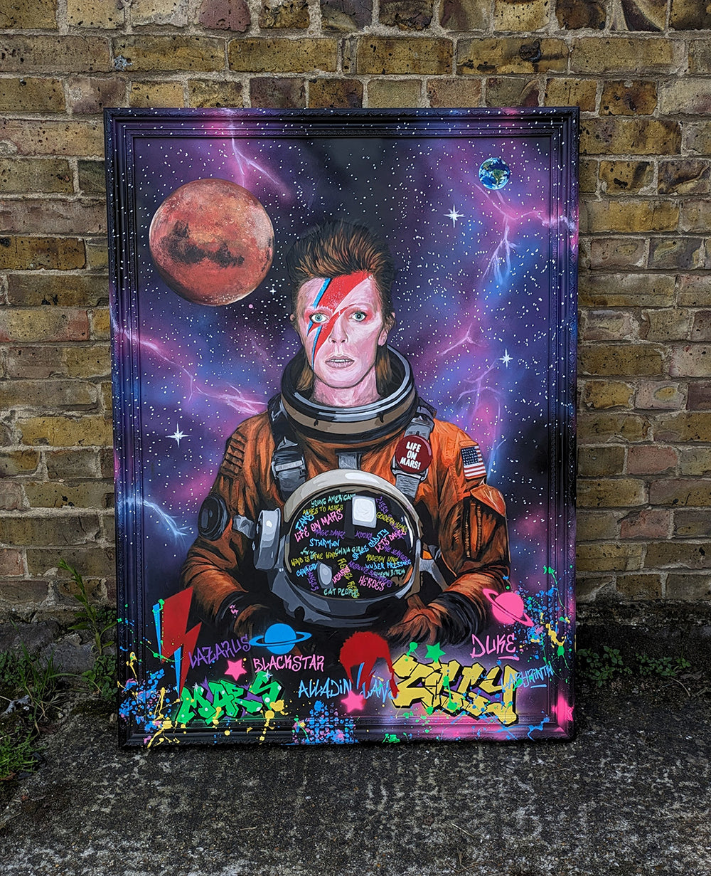 Limited edition embellished art print of David Bowie in a retro orange NASA-style spacesuit set against a vivid cosmic backdrop, featuring Mars and Earth, graffiti elements, and Bowie’s iconic lightning bolt makeup, created by KiPS.art and printed on 3mm Foamex.