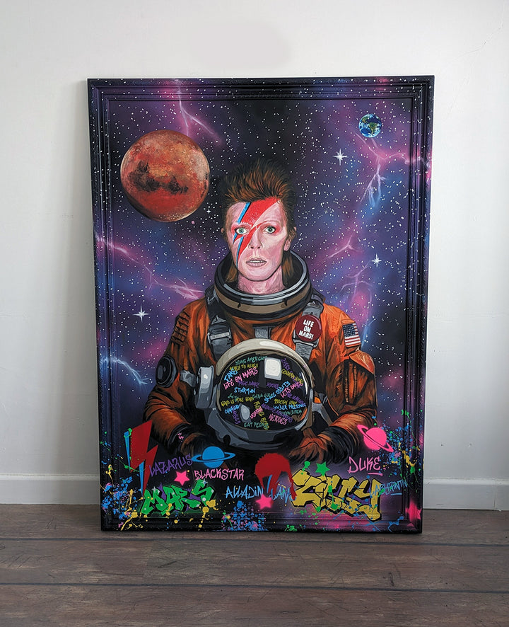 Limited edition embellished art print of David Bowie in a retro orange NASA-style spacesuit set against a vivid cosmic backdrop, featuring Mars and Earth, graffiti elements, and Bowie’s iconic lightning bolt makeup, created by KiPS.art and printed on 3mm Foamex.