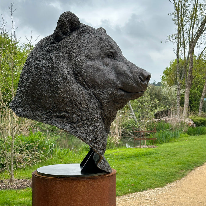 Large bronze head study of a Kodiak brown bear by Nick Bibby, showing powerful form, dense textured fur and rich brown patina, mounted on a tall bronze plinth with mottled green and earthy tones.