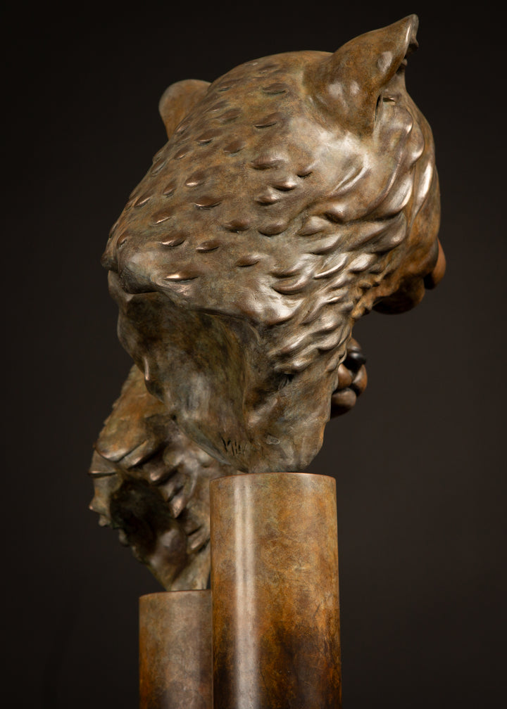 Kulina cheetah mother and cub bronze sculpture by Min Reid, tender wildlife sculpture showing a protective cheetah nuzzling her cub, warm golden brown bronze patina mounted on tall cylindrical bronze plinths against a dark background