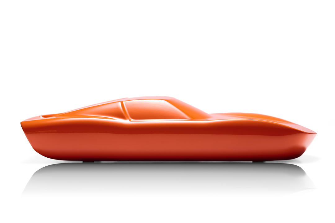 ‘Lamborghini Miura’ by Srini Gandra, a limited-edition contemporary automotive sculpture from the Forme di Velocità series, inspired by the legendary Lamborghini Miura designed by Marcello Gandini at Bertone. Presented in a vibrant high-gloss Arancio Miura orange finish, the sculpture captures the supercar's low, flowing silhouette, elongated bonnet, sculpted wheel arches, sweeping side contours and distinctive fastback profile. Its smooth, minimalist surfaces celebrate the aerodynamic elegance and timeless