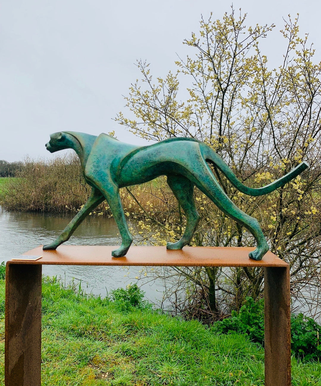 Marie Ackers The Walking Cheetah bronze sculpture in verdigris green patina, limited edition of 8. Stylised cheetah mid-stride, long tail extended, capturing elegance, rhythm, and the essence of feline movement in contemporary bronze.