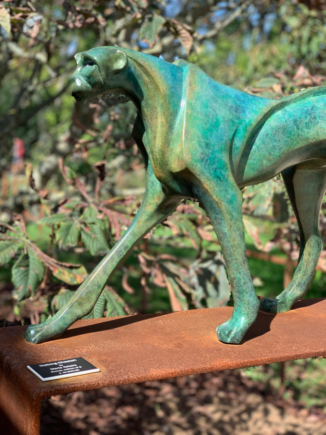 Marie Ackers The Walking Cheetah bronze sculpture in verdigris green patina, limited edition of 8. Stylised cheetah mid-stride, long tail extended, capturing elegance, rhythm, and the essence of feline movement in contemporary bronze.