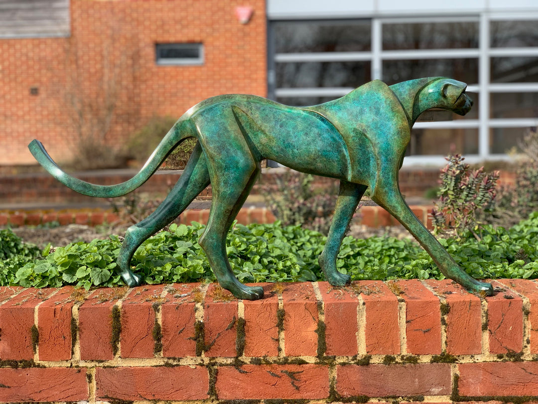 Marie Ackers The Walking Cheetah bronze sculpture in verdigris green patina, limited edition of 8. Stylised cheetah mid-stride, long tail extended, capturing elegance, rhythm, and the essence of feline movement in contemporary bronze.