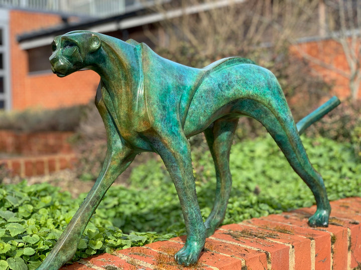 Marie Ackers The Walking Cheetah bronze sculpture in verdigris green patina, limited edition of 8. Stylised cheetah mid-stride, long tail extended, capturing elegance, rhythm, and the essence of feline movement in contemporary bronze.