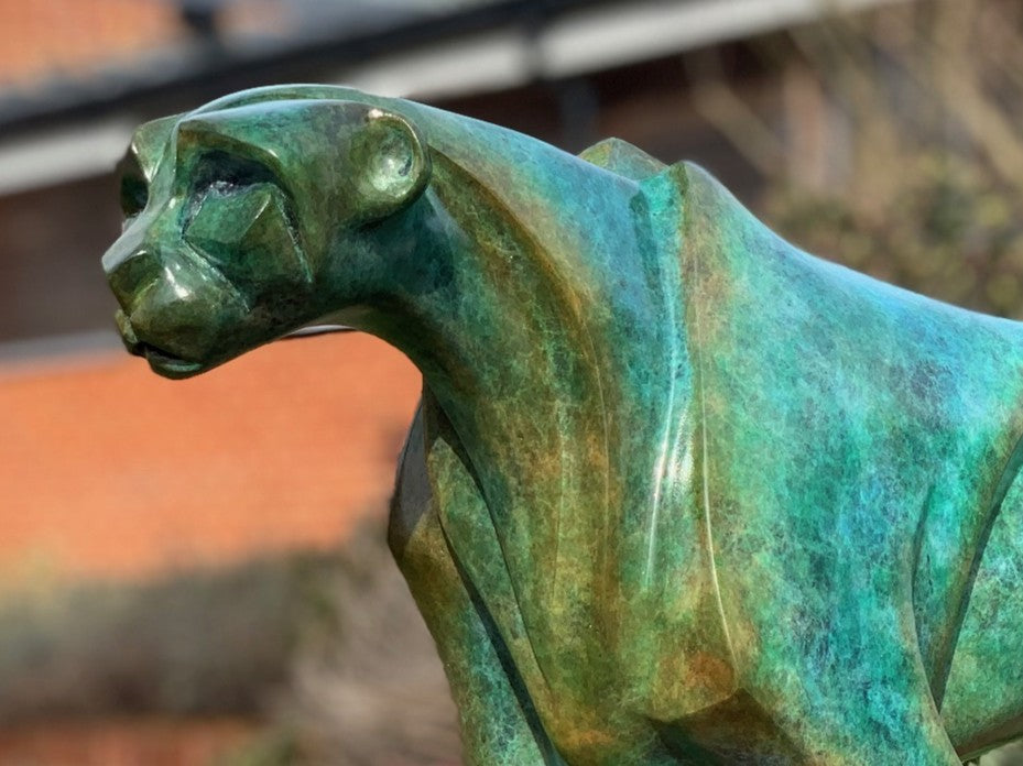 Marie Ackers The Walking Cheetah bronze sculpture in verdigris green patina, limited edition of 8. Stylised cheetah mid-stride, long tail extended, capturing elegance, rhythm, and the essence of feline movement in contemporary bronze.