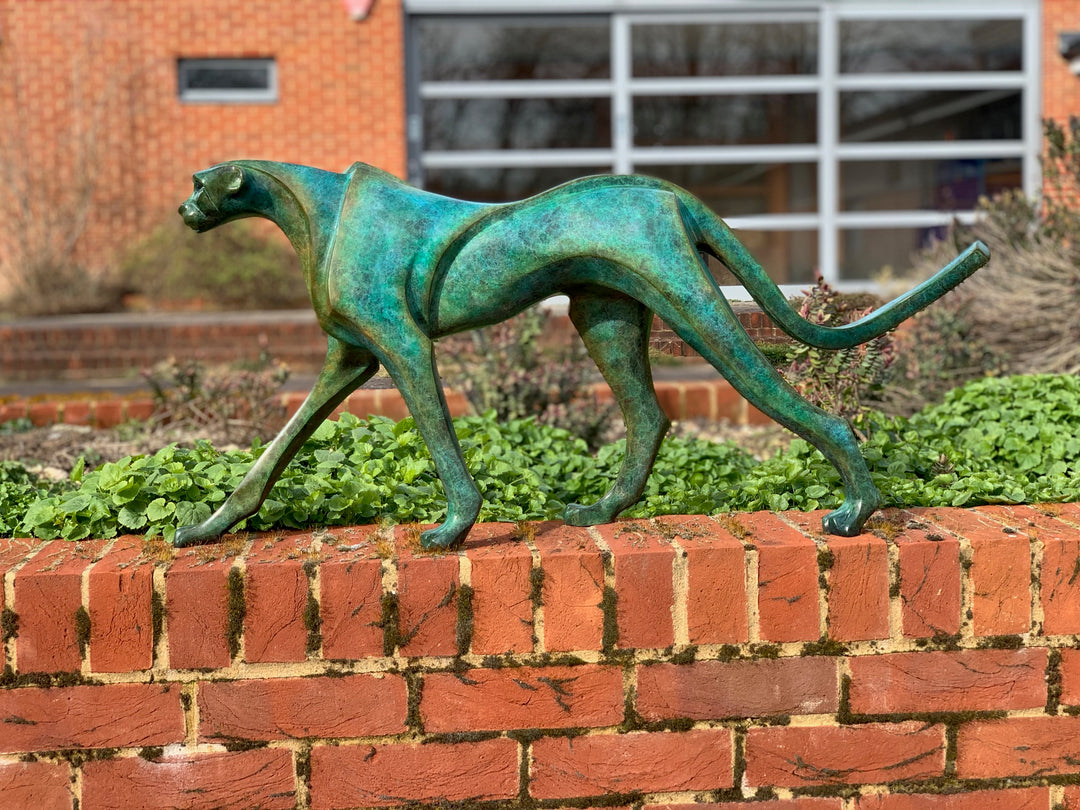 Marie Ackers The Walking Cheetah bronze sculpture in verdigris green patina, limited edition of 8. Stylised cheetah mid-stride, long tail extended, capturing elegance, rhythm, and the essence of feline movement in contemporary bronze.