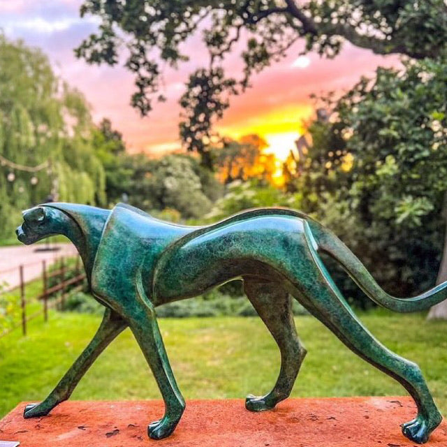 Marie Ackers The Walking Cheetah bronze sculpture in verdigris green patina, limited edition of 8. Stylised cheetah mid-stride, long tail extended, capturing elegance, rhythm, and the essence of feline movement in contemporary bronze.
