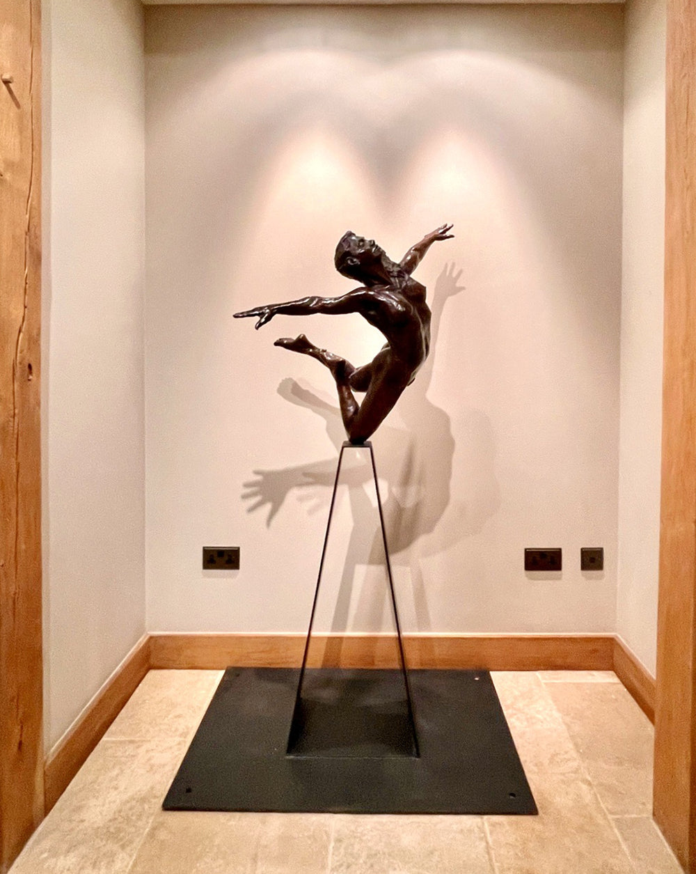 Teresa Wells’ bronze sculpture Liberty (2019), limited edition of 12, depicting a nude female figure in a dynamic leap with arms and head thrown back, one leg extended and the other bent mid-air. Cast in warm patinated bronze and mounted on a tall, powder-coated steel plinth, the piece balances elegance, athleticism, and expressive movement. At 98cm × 60cm × 190cm and 95kg, it is suited for both interior display and sheltered outdoor settings, with fine anatomical detailing smooth contours.