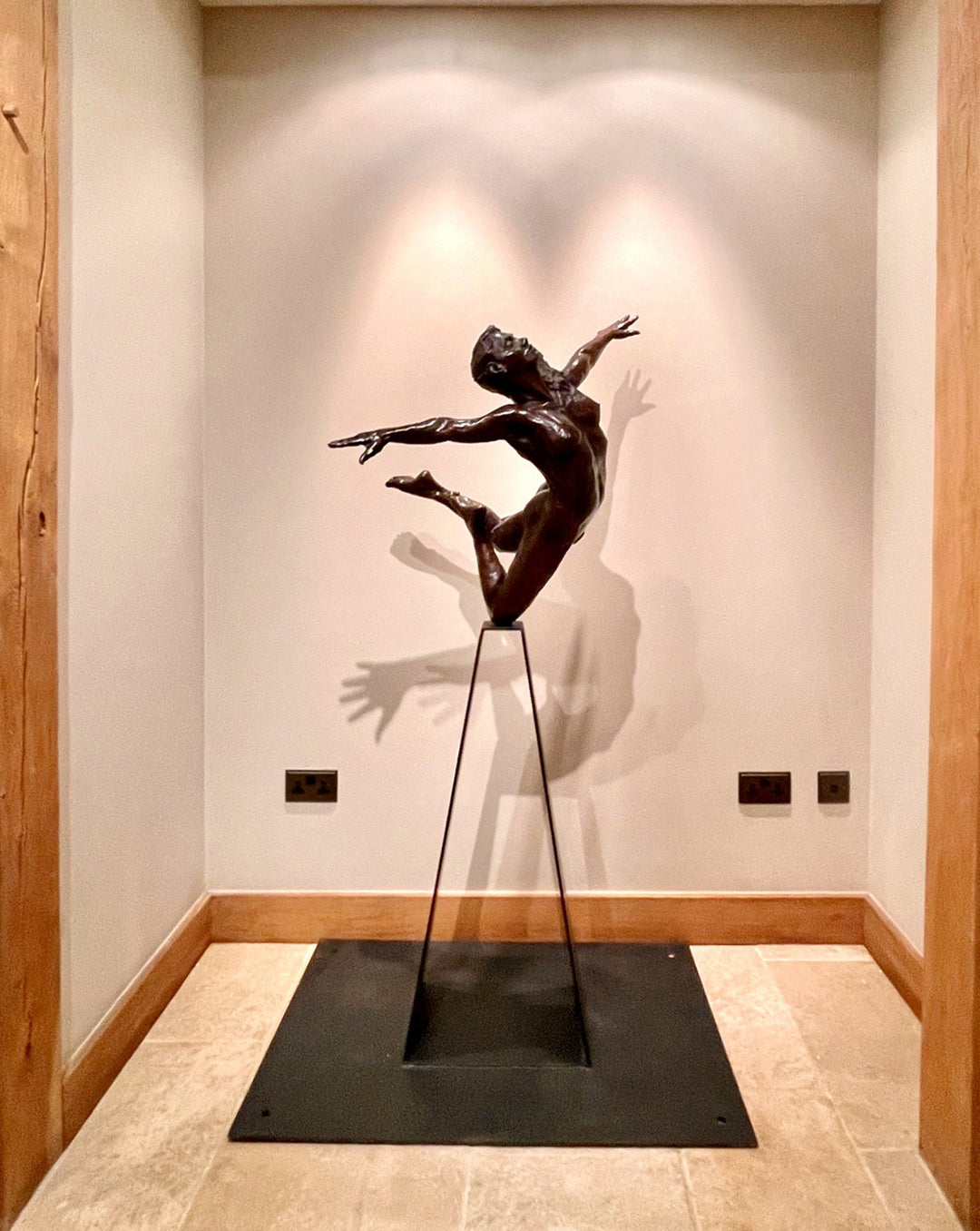 Teresa Wells’ bronze sculpture Liberty (2019), limited edition of 12, depicting a nude female figure in a dynamic leap with arms and head thrown back, one leg extended and the other bent mid-air. Cast in warm patinated bronze and mounted on a tall, powder-coated steel plinth, the piece balances elegance, athleticism, and expressive movement. At 98cm × 60cm × 190cm and 95kg, it is suited for both interior display and sheltered outdoor settings, with fine anatomical detailing smooth contours.